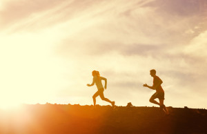 Silhouette of Man and woman running together into sunset, Wellness fitness concept